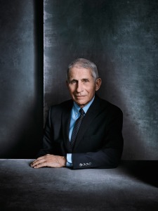 Portrait of older white man wearing powder blue collared shirt, navy blue suit and a navy tie with white dots.