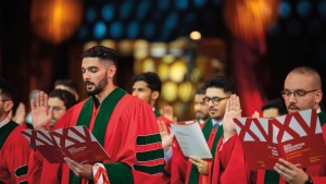 Middle Eastern men in red and green robes at Weill Cornell Medicine-Qatar swear the Hippocratic Oath with their right hands up.