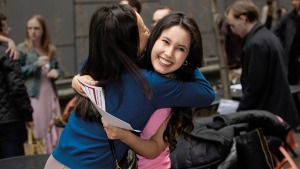 Two smiling, fair-skinned young women hug.