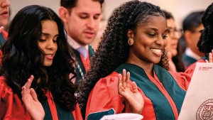 Students in red, green and black graduation robes with their right hands up