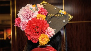 Closeup of black mortarboard decorated with flowers and the word “Cornell”
