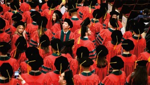 Overhead view of students in red, green and black graduation robes and mortarboards