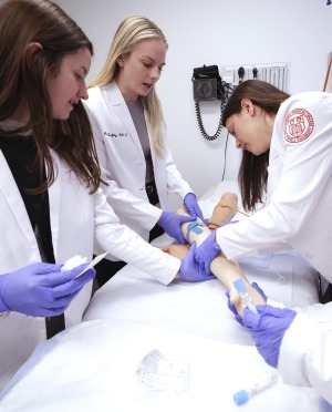 Students practice inserting an intravenous catheter.